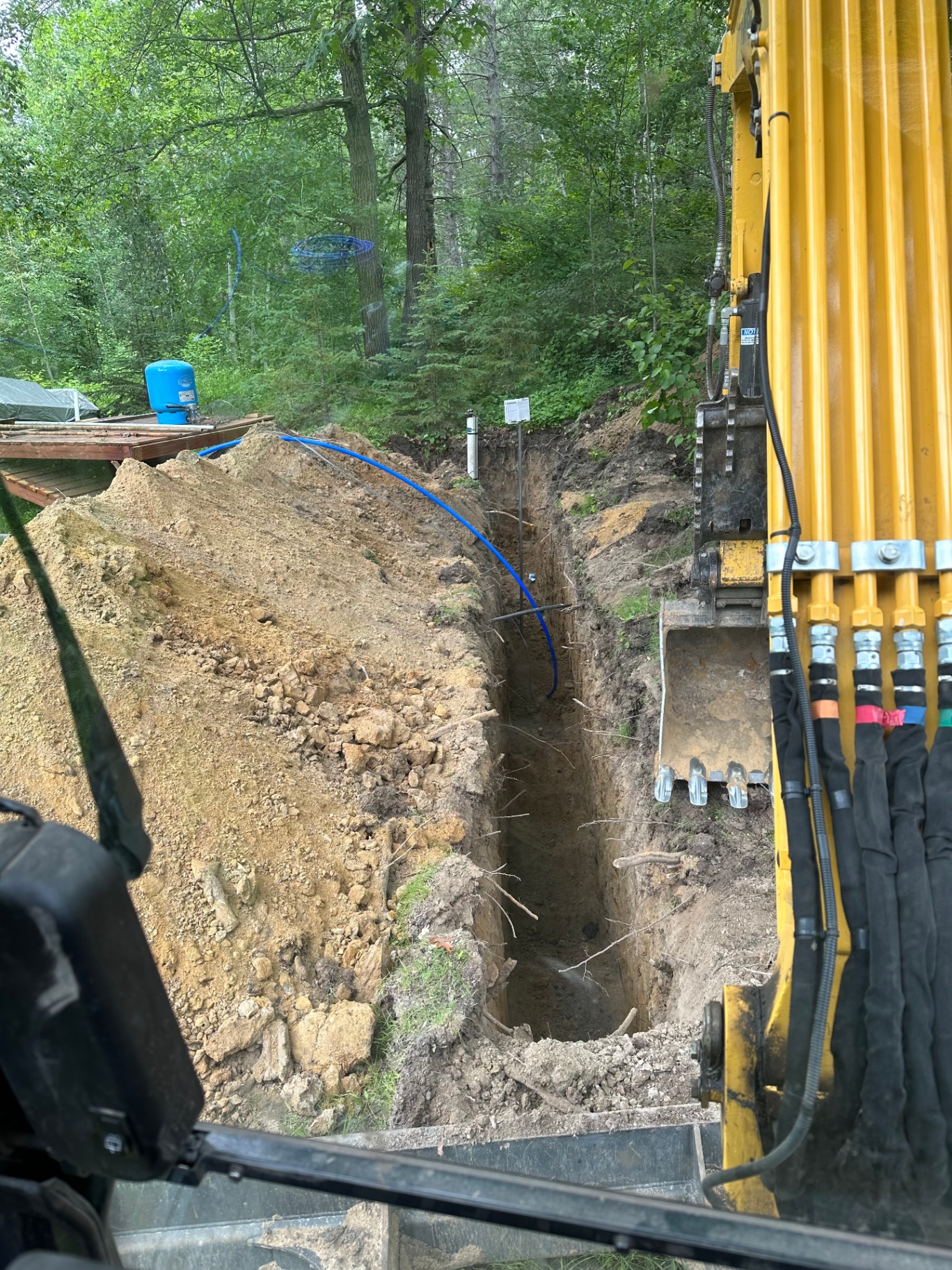 Excavator trenching a waterline to a cabin